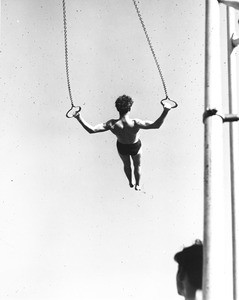 A gymnast practices his ring routine in the middle of a very busy Los Angeles playground