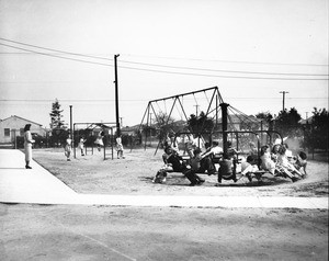 A group of children play in a Los Angeles playground, as a single women keeps an eye on them