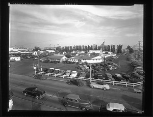 Looking at Farmers Market and its parking lot full of cars from the corner of Third Street and Fairfax Avenue