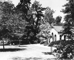 A family picnic in a park-like landscape next to a Spanish-style building