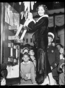 Nancy Carroll at switchboard turning on Christmas street light, Southern California, 1929