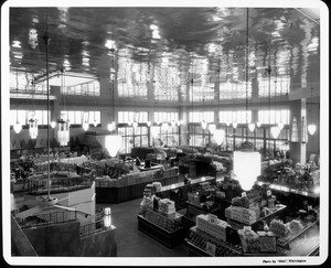 The interior of a grocery store before it opens showing the merchandise in display cases and people looking in through the windows