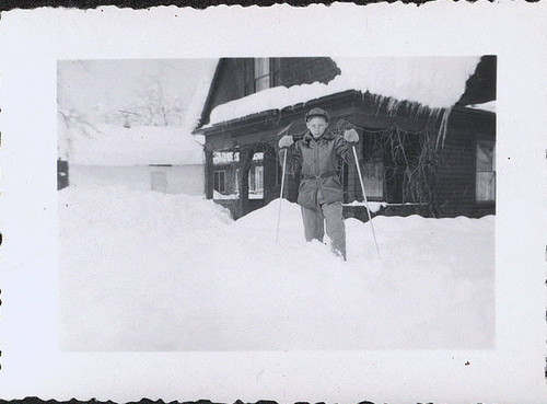 Boy skiing outside snow covered cabin