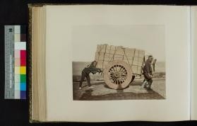 Photograph of men pushing a cargo cart