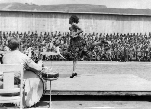 Stage entertainment with musicians and male dancer in female dress, San Quentin Little Olympics Field Meet, 1930 [photograph]