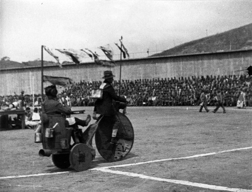 Entertainment featuring clowns with a handmade, high-wheeler tricycle, San Quentin Little Olympics Field Meet, 1930 [photograph]