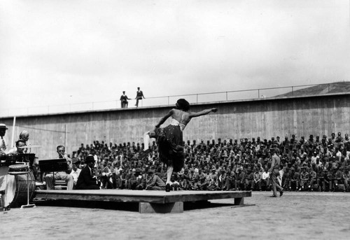 Male performer in female dress, dancing on stage, San Quentin Little Olympics Field Meet, 1930 [photograph]