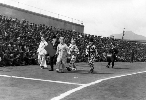 Small group of clowns parading before spectators, San Quentin Little Olympics Field Meet, 1930 [photograph]