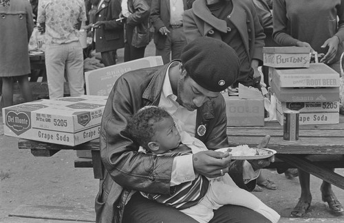 Black Panther feeding son, at Free Huey Rally, De Fremery Park, Oakland, CA, #29 from A Photographic Essay on The Black Panthers