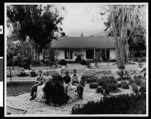 Four young boys sitting in front of the restored adobe of Sheriff Don Tomas Sanchez in San Rafael Park, Glendale, ca.1940