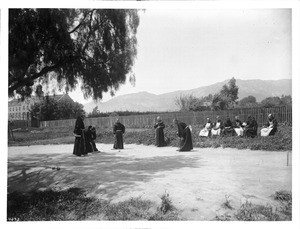 Six Franciscan monks look on as five others play croquet at Mission Santa Barbara, ca.1904