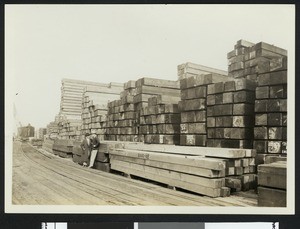 Man and women leaning against lumber at the E.K. Wood Lumber Company, ca.1930