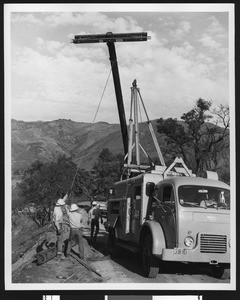 Electrical workmen erecting a power pole, ca.1950