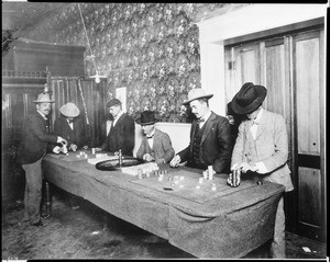 Interior view of a gambling hall showing a roulette table with $20,000 in gold (or chips?) on the table, ca.1900