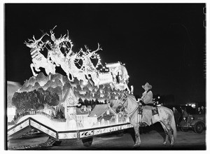 Man on horseback beside a Christmas display featuring reindeer