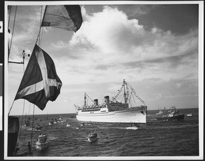 Matson Lines passenger steamer at sea, showing numerous small boats in the water nearby, ca.1920-1960