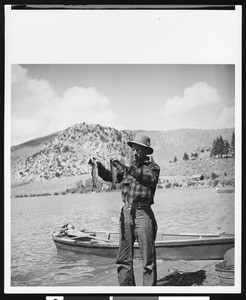 Man holding up two fish at Gull Lake, ca.1930
