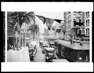 View of Broadway from Fourth Street to Fifth Street during a Shriners Parade, showing flags, automobile, and streetcars, ca.1925