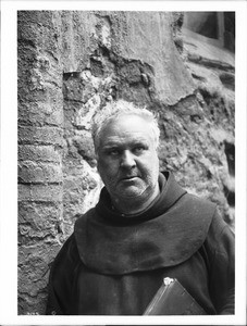 Close-up of Father Superior O'Keefe standing in the ruins of the mortuary chapel of Mission San Luis Rey de Francia, California, 1904