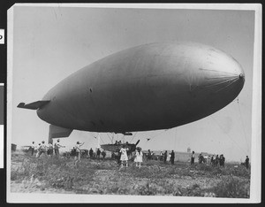 Large airship being held down by cables as spectators surround it at a "balloon school" in Arcadia, ca.1915