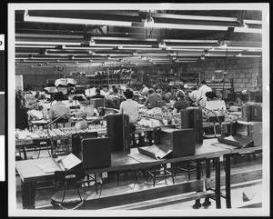 Interior view of an unidentified factory,showing workers from behind, ca.1940