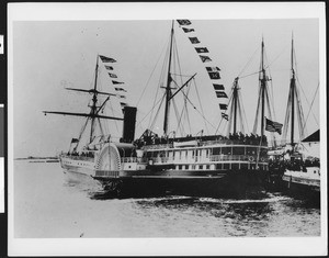 Side wheel steamer Orziba near a dock or harbor, ca.1885
