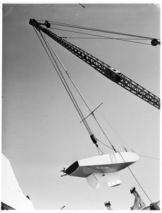 Freighter arm hefting what appears to be a boat rudder