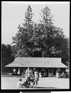 Relaxing in front of a cabin, ca.1910