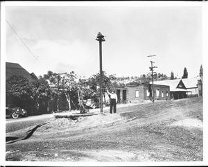 Man attending to Coulterville's fire alarm, a bell on a pole, ca.1930