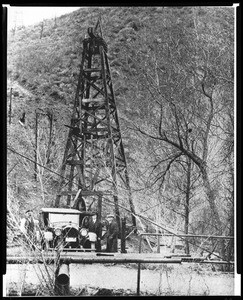 Half-tone image depicting an automobile in front of California's first producing oil well, June 1, 1928