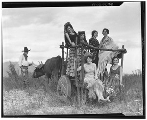 Women on a cart lead by an ox and cowboy for the La Fiesta de Los Angeles, ca.1920