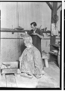 Sculptor putting the finishing touches on a large bust of a man