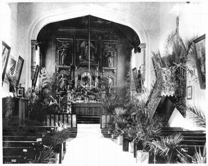 Interior view of Mission San Gabriel, looking down the middle aisle towards the altar, ca.1895