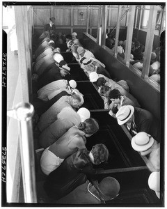 People looking into long troughs, possibly on a glass bottom boat