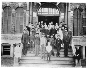 Portrait of students posing with their teachers in front of Baptist College, ca.1900