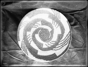 Indian basket displayed against a cloth backdrop, ca.1900