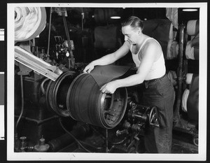 Worker laying down the first plies of a passenger car tire at the Goodyear Tire and Rubber Company's plant, ca.1930