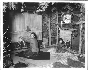 Portrait of an older Navajo Indian woman and a young Navajo Indian girl weaving blankets, ca.1908