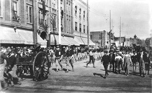 Veterans "Teddy's Terrors" marching in a parade with their canon, ca.1904