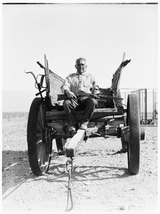 A man sitting in a wagon holding a gun