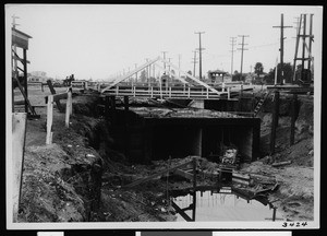 Construction below a small, unidentified wooden bridge