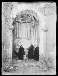 Father O'Keefe and two neophyte monks standing at the old altar in the mortuary chapel at Mission San Luis Rey de Francia, August 2, 1900