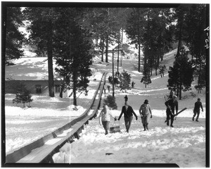 Ski jumping at Big Pines Recreation Camp, showing people climbing up a hill, 1929