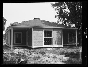 An exterior view of a one-story house, showing wide sliding windows