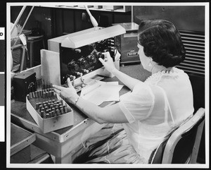 Close-up view of woman worker handling a panel with knobs at Ircal Industries, ca.1940