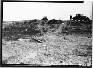 Two automobiles parked on top of a sandy hill