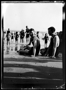 Bathers sitting on the sand near an ocean