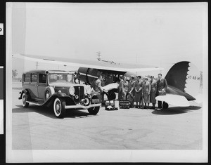 Patient on a stretcher being put into a medical airplane while six nurses and a doctor stand beside the craft, ca.1933