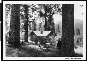 A family resting outside a mountain cabin at Camp Radford, ca.1930