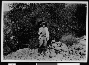 Man standing near a hat marking the spot where gold was first discovered in Placerita Canyon